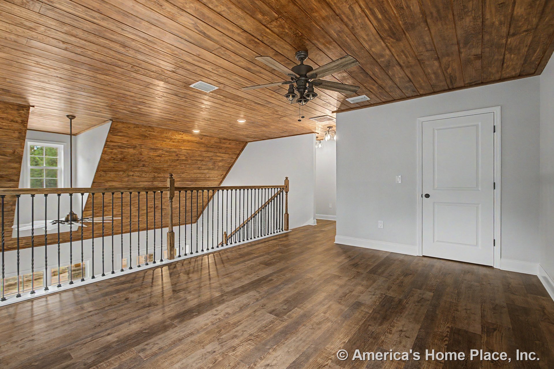 Upstairs loft with wood plank ceiling, matching wood floors, wrought iron open stair railing, ceiling fan with lights, recessed lighting, white trim and baseboards, single panel