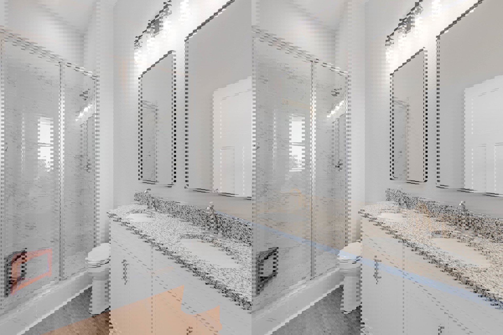 Bathroom with marble countertops, glass-enclosed shower, tile flooring, wooden corner shelf, wall-mounted mirror, white paneled door, and modern plumbing fixtures