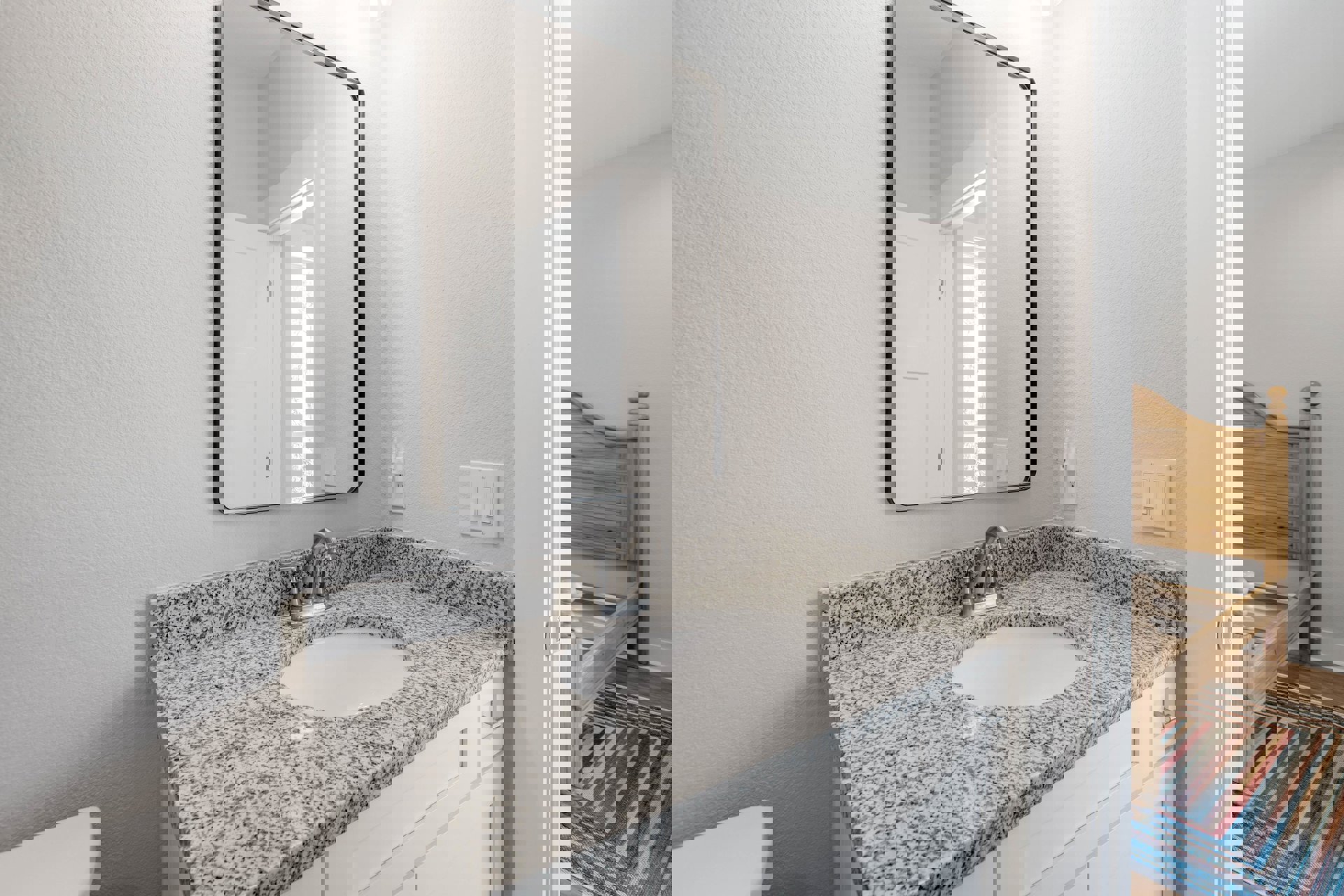 White ceramic sink with chrome faucet set in a wood vanity, rectangular wall mirror above, patterned rug on light wood floor, white tile backsplash, and cabinetry with drawers.