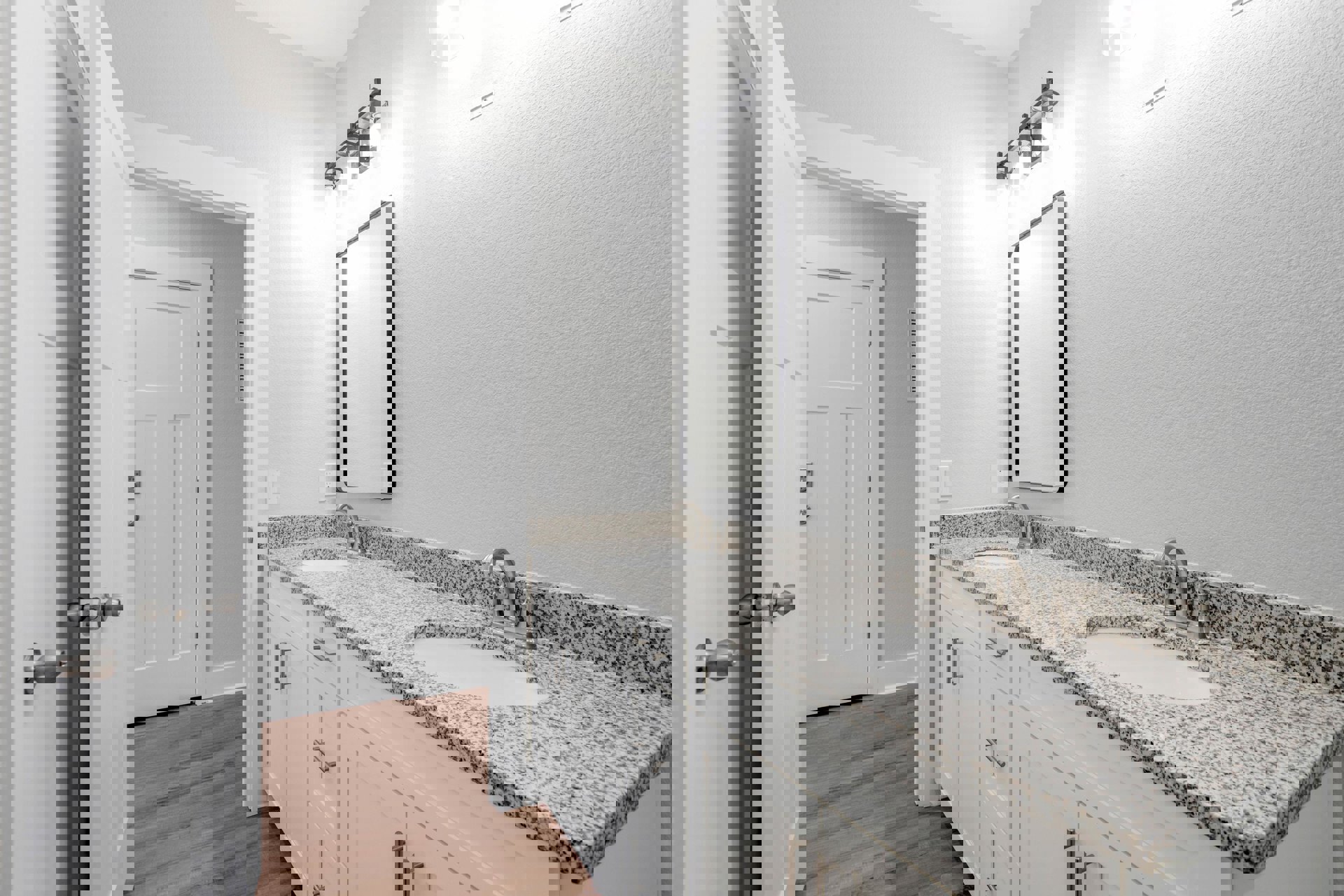 Bathroom with two undermount sinks set in a light stone countertop, wide framed mirror above, white cabinetry below, chrome faucets, and neutral tile backsplash.