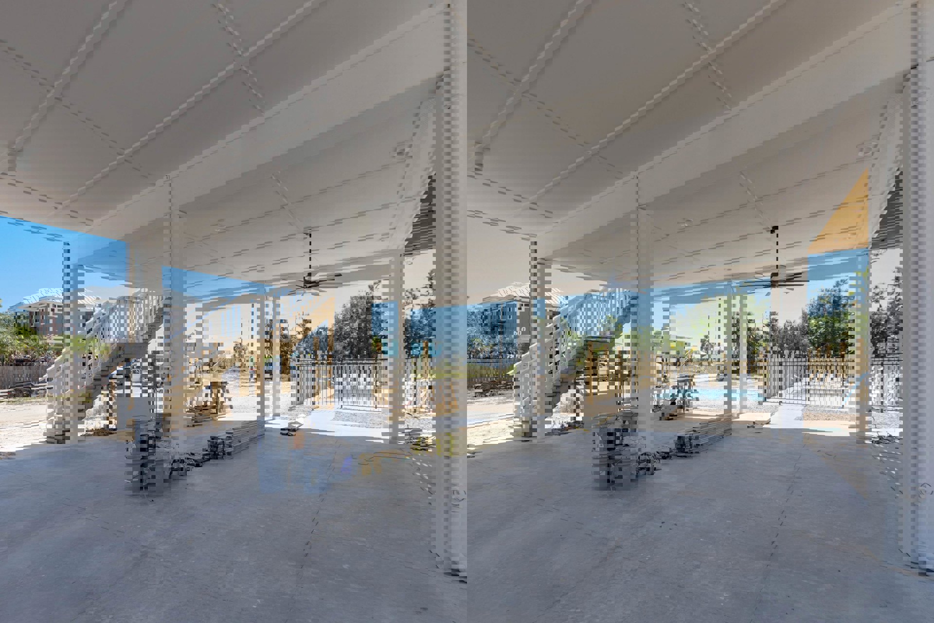 Modern home under construction featuring a partially finished pool, white staircase with matching railing, exposed wood beams, construction materials, and a white ceiling with grid