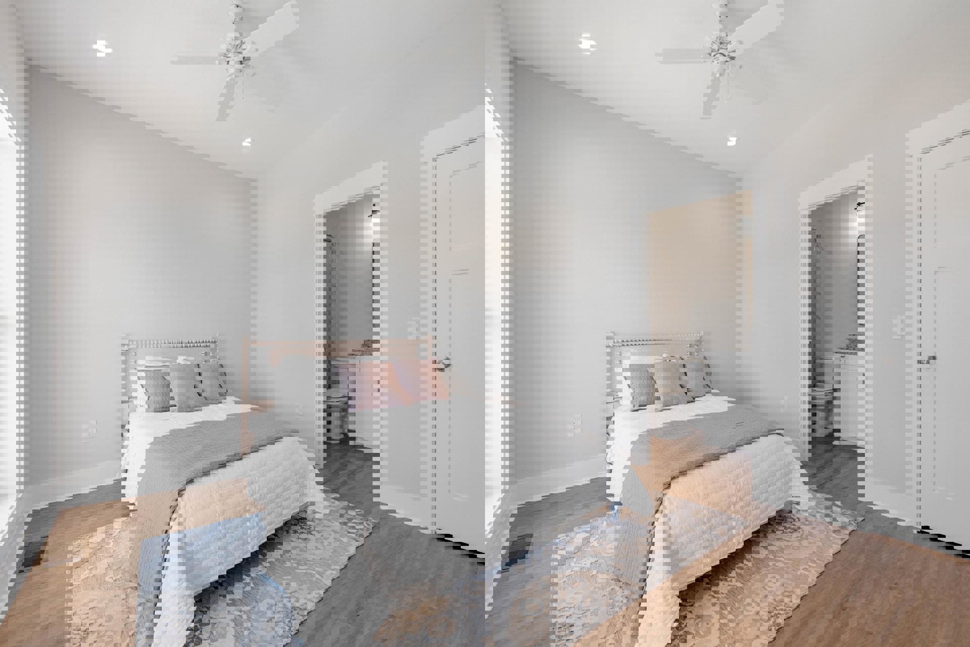 Bedroom with white ceiling fan, bed dressed in white and pink pillows, light walls, and hardwood flooring