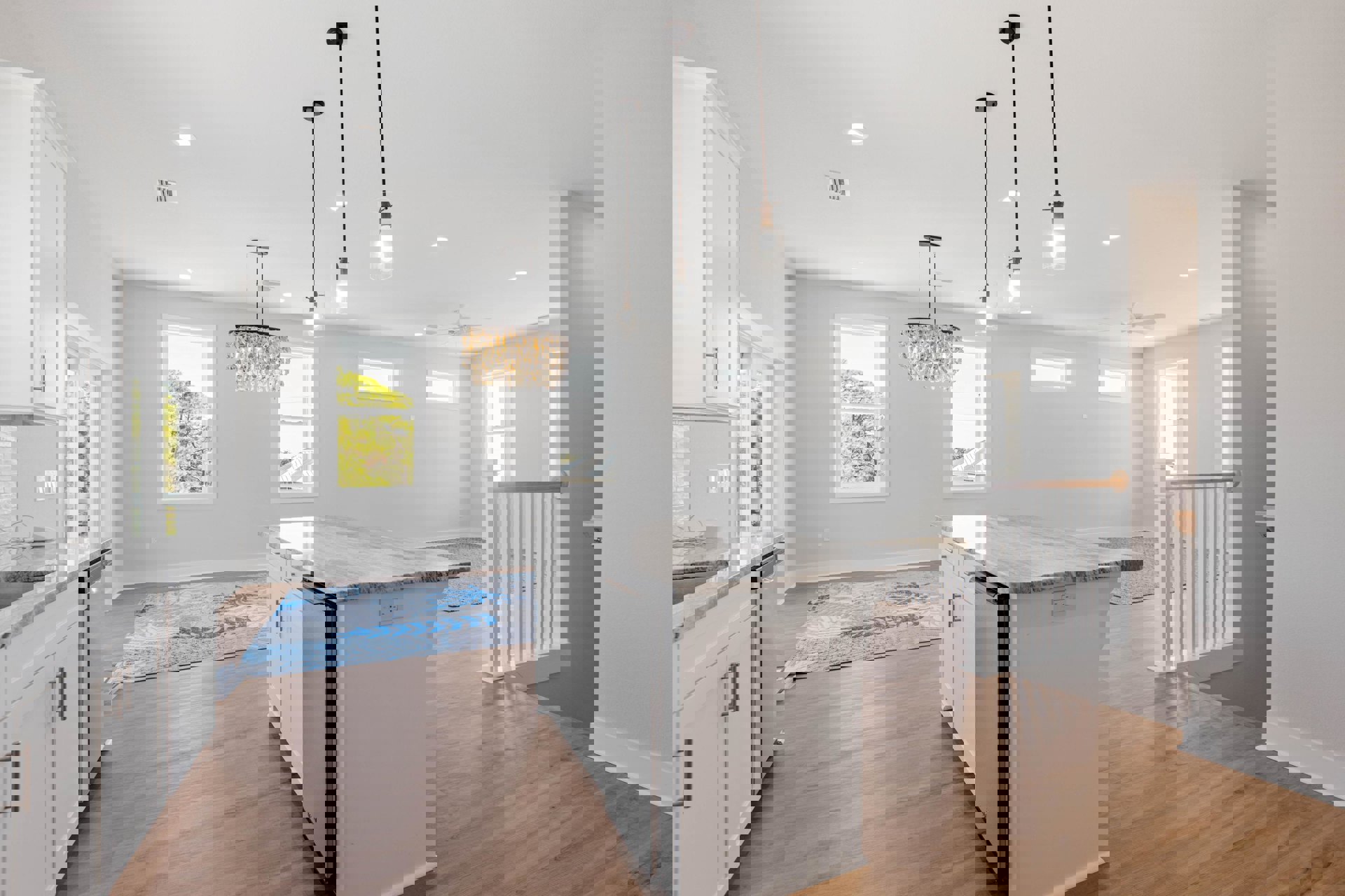 Kitchen with large island featuring stone countertop, stainless refrigerator, cabinetry, sink, and oyster shell chandelier; window overlooks trees, patterned rug covers hardwood