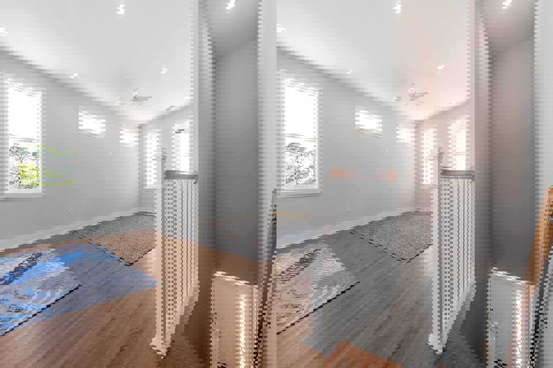 Carpeted room featuring a wooden staircase, large window overlooking trees, area rug on the floor, and wood-framed wall accents