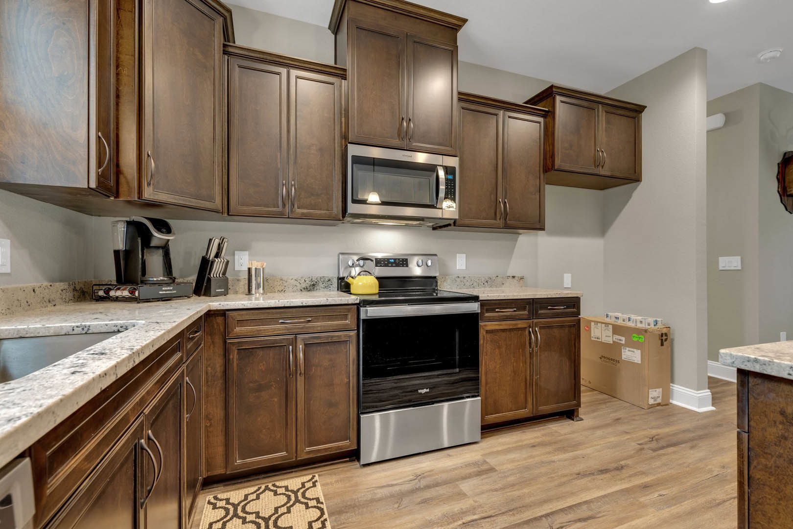 Kitchen with dark wood cabinets, stainless steel stove and oven, built-in microwave, light-colored countertops, and overhead lighting