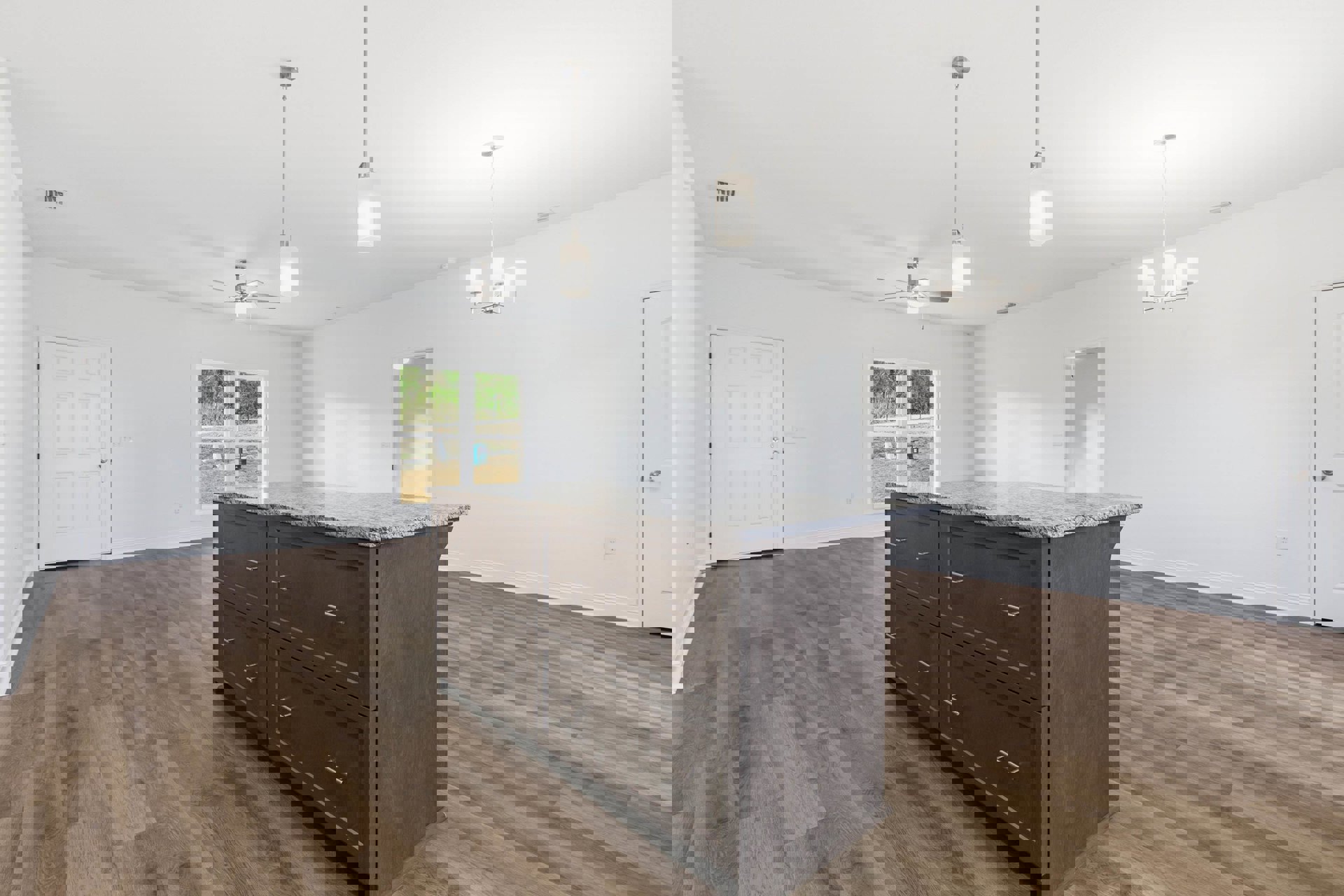 Quartz kitchen island with wood drawers, white cabinetry, silver hardware, hardwood flooring, and white walls with framed door.