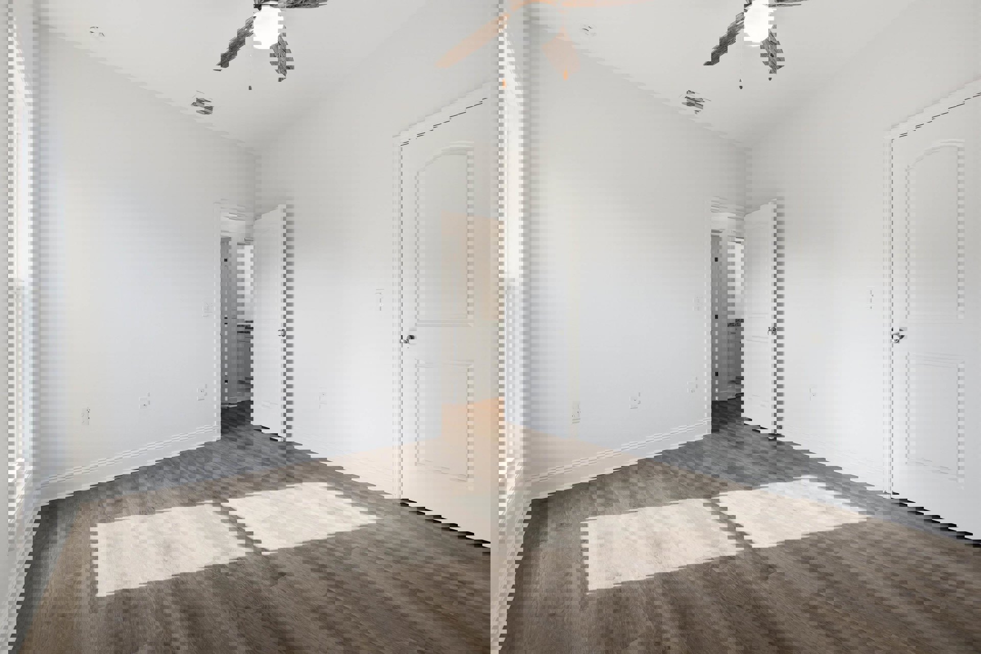 Ceiling fan with light fixture above wood laminate flooring, open white door with silver knob, white rectangular window frame, smooth plaster walls and ceiling