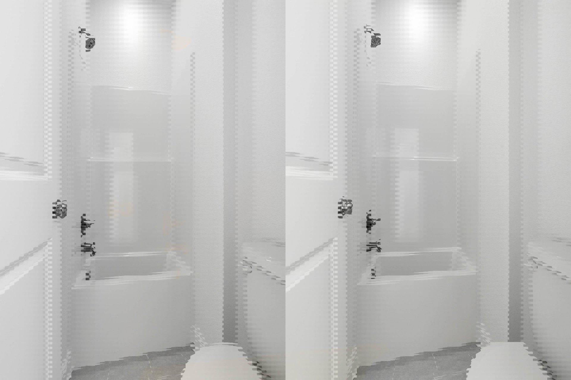 White bathroom with tiled floor, silver faucet bathtub, wall-mounted toilet, glass shower enclosure, chrome showerhead, and white door with metal knob.