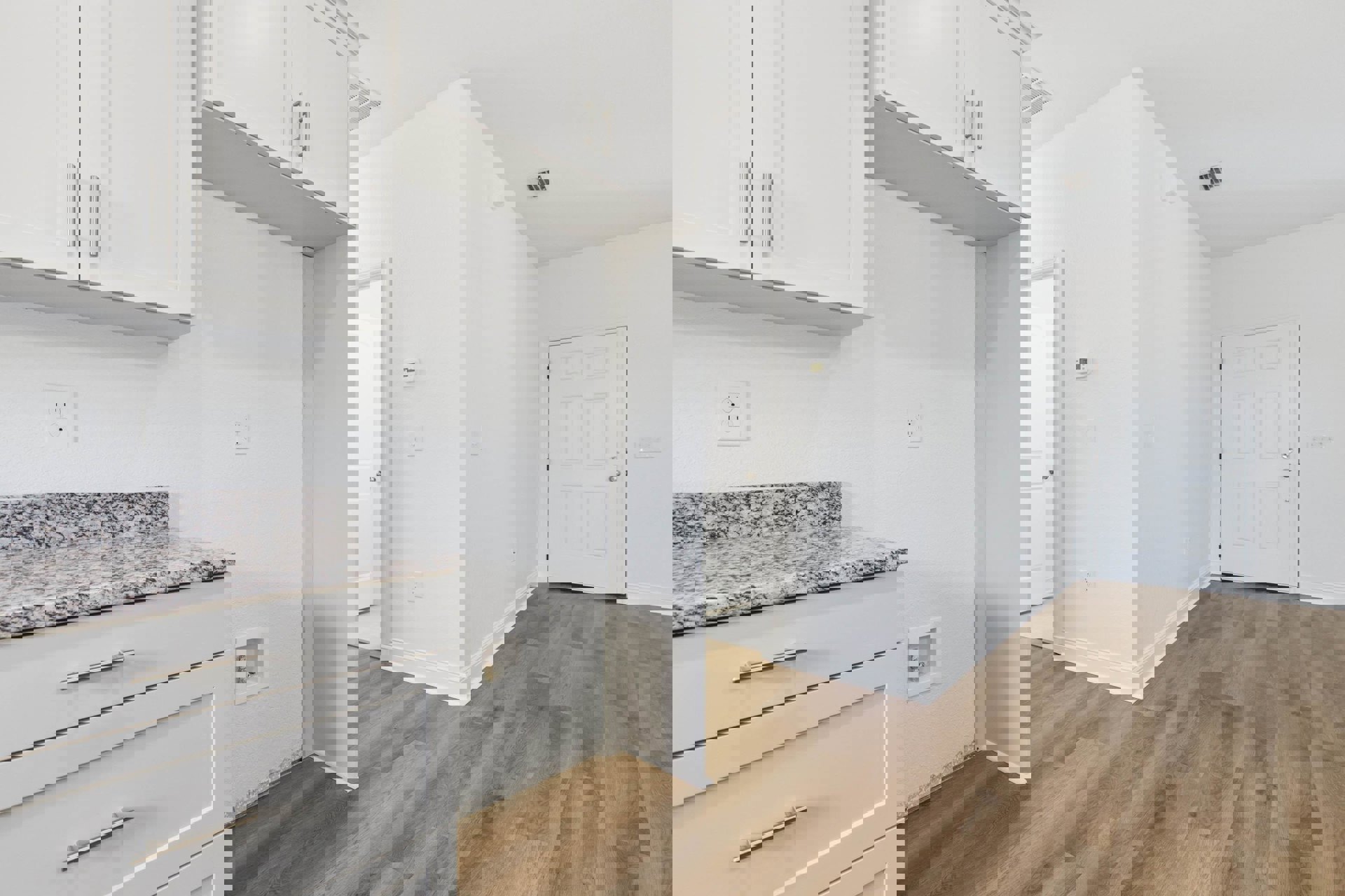 White kitchen with white cabinets, marble countertop, wood laminate flooring, silver door knobs, built-in square shelf displaying a small statue, electrical outlet visible on wall.