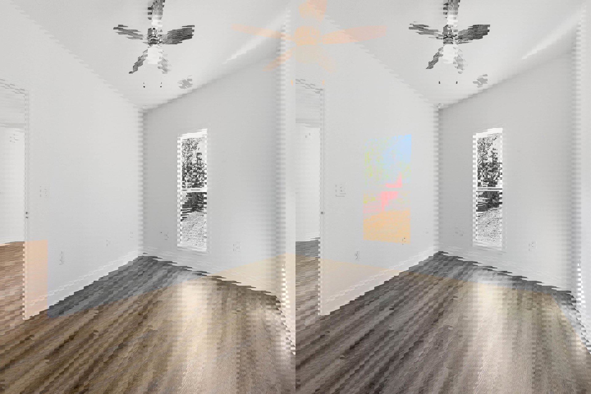 Living room with wood flooring, white plaster walls, ceiling fan with light, large window, and red upholstered bench beneath the window