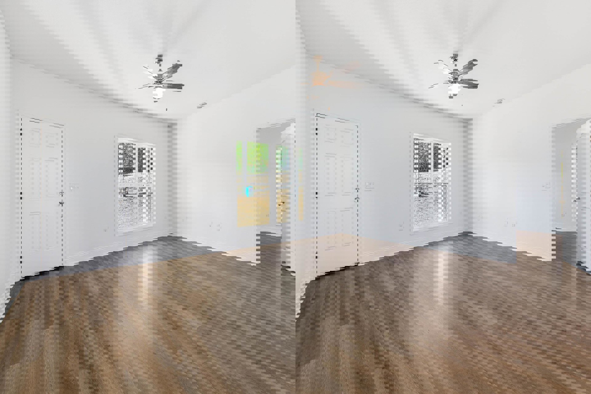 Ceiling fan with light fixture, hardwood floor, white door with silver knobs, window overlooking yard, plaster walls