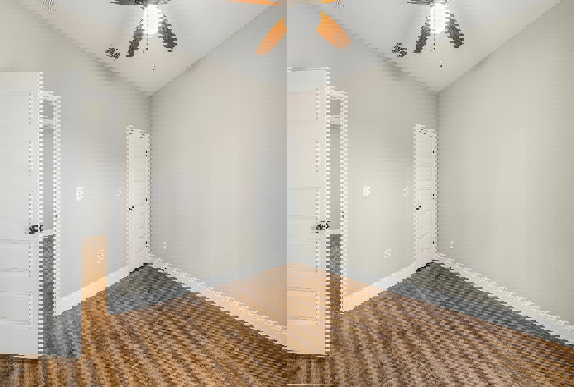 Ceiling fan with light fixture, wood laminate flooring, white walls, white door with black hardware