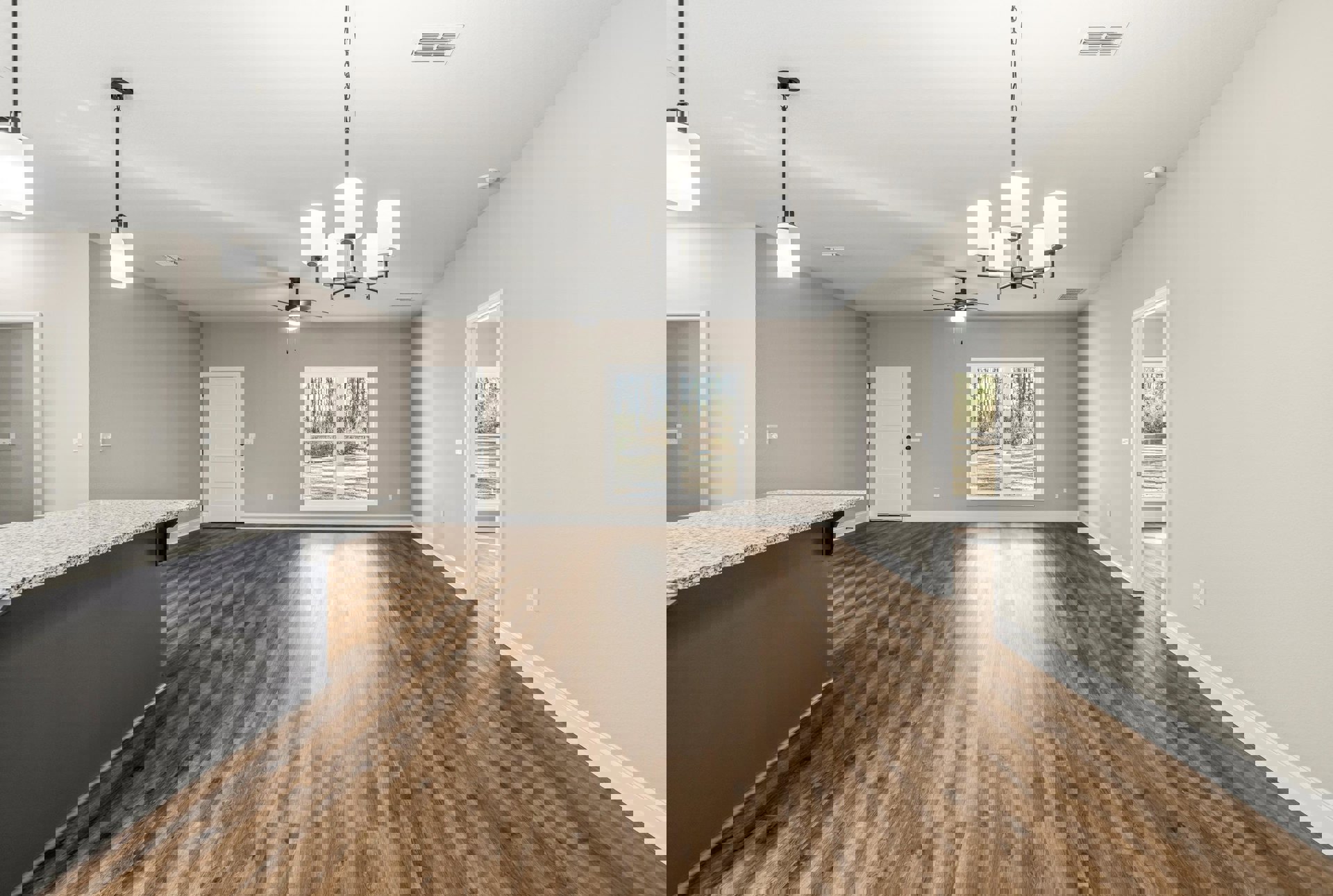 Hardwood floor room with marble countertop, white door with black knobs, large window showing trees, black track lighting fixture on ceiling