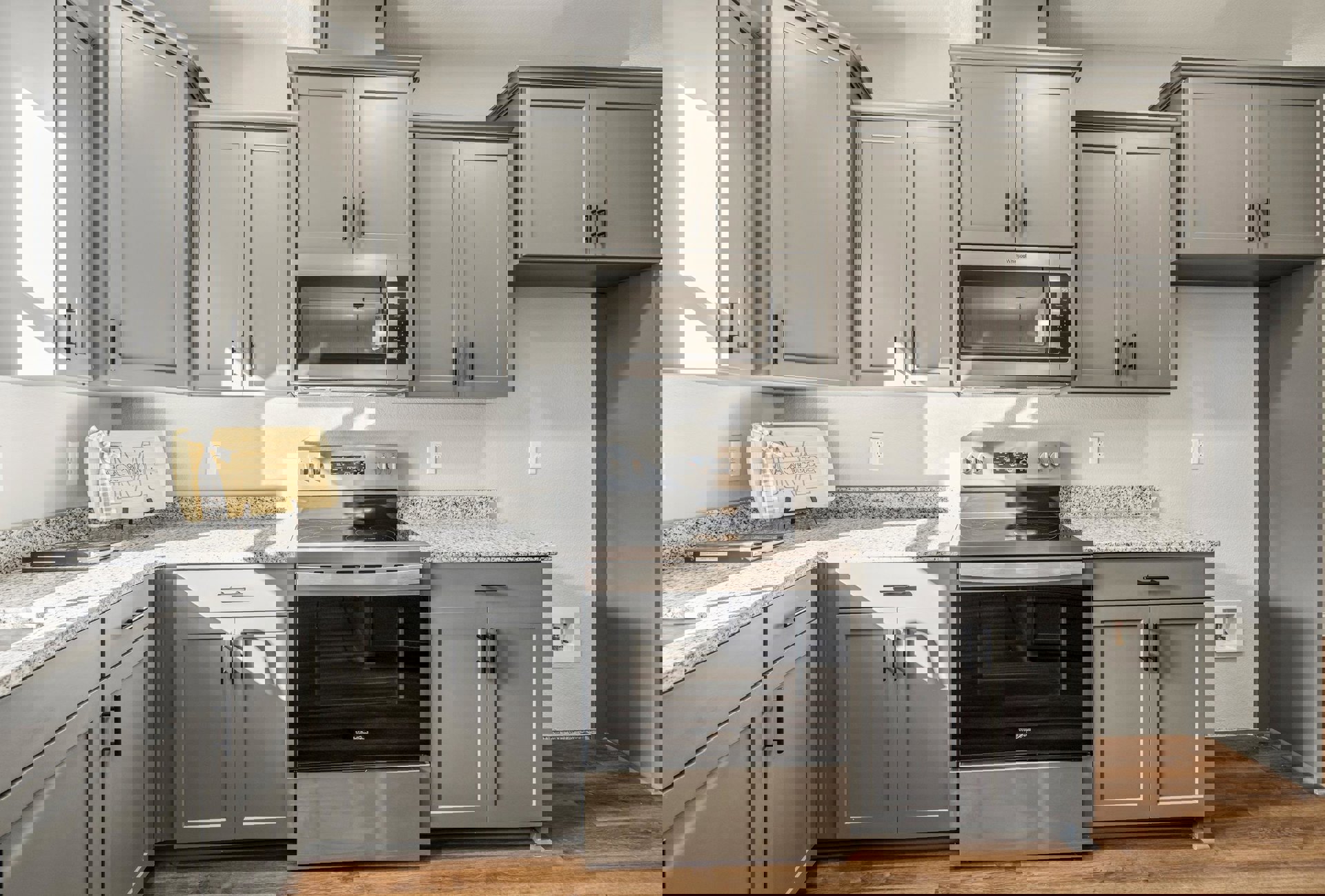 Grey shaker cabinets and stainless stove with glass door, white quartz countertops, wood sign with bow on wall, pendant ceiling light, small decorative figure on backsplash.