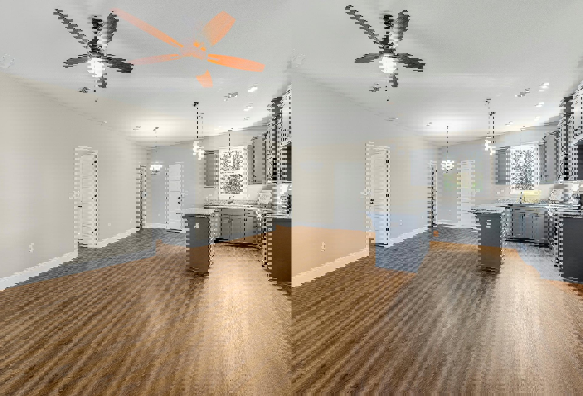 Open-concept kitchen with marble-topped island, wood flooring, ceiling fan with light, dining table, and white door with black hardware