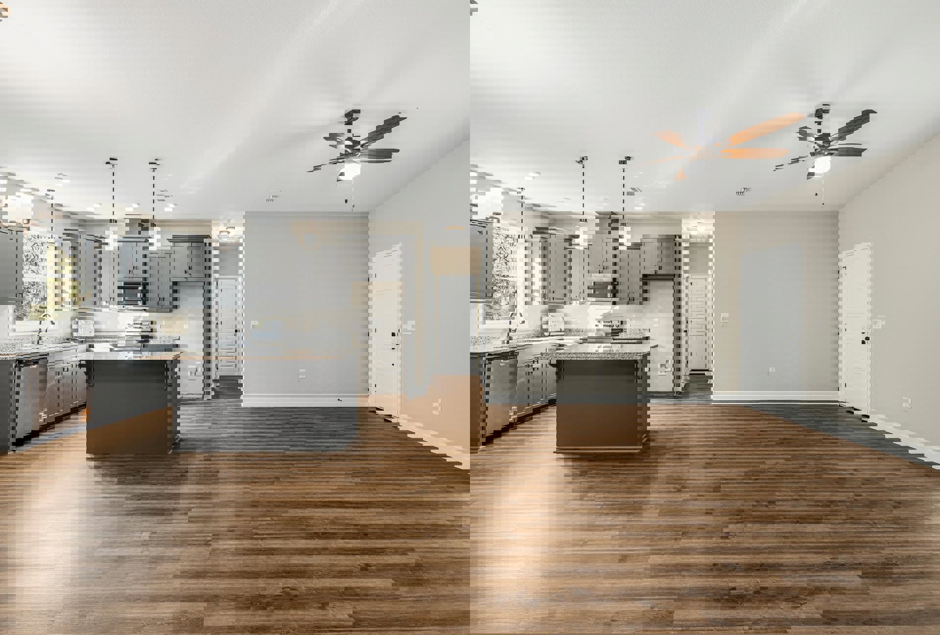 Open-concept kitchen and living room featuring wood flooring, white walls, ceiling fan with light, white door with black knobs, kitchen counter with stove, cabinetry, stainless