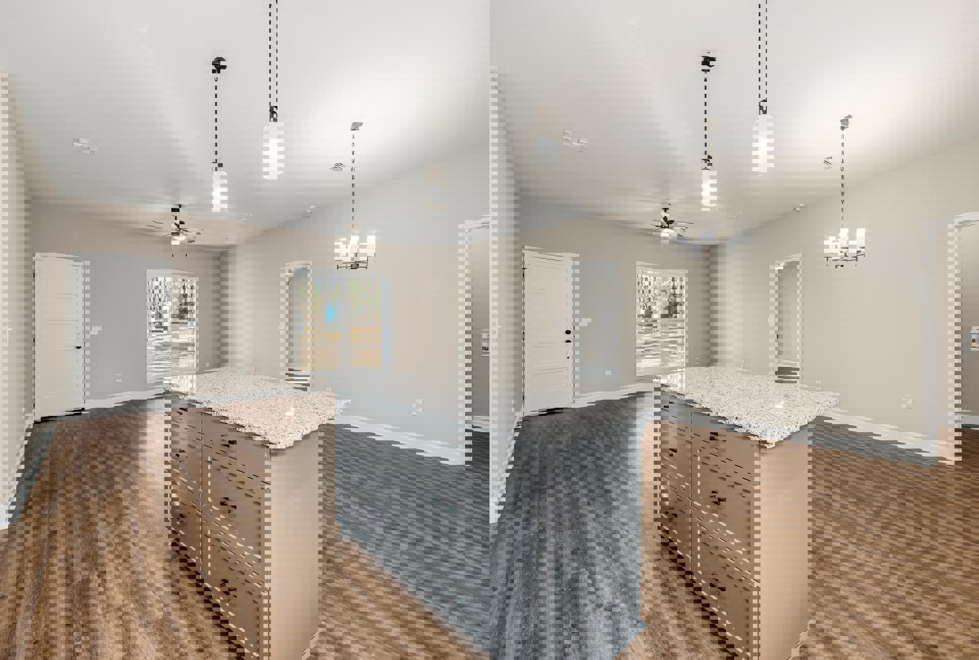 Kitchen island with drawers on wood flooring, white cabinetry with black handles, white door with matching frame, window overlooking forest, rectangular ceiling light fixture