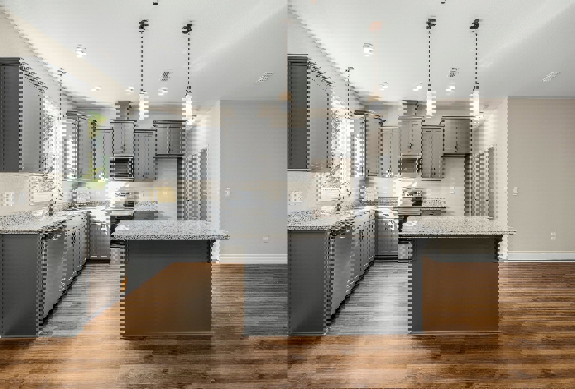 Spacious kitchen featuring a large central island with stone countertop, white cabinetry, stainless steel refrigerator, tile backsplash, and modern pendant lighting