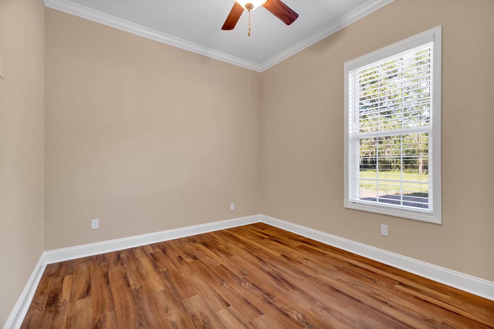 Wood flooring with white trim, ceiling fan and light fixture, window with white blinds, plaster walls
