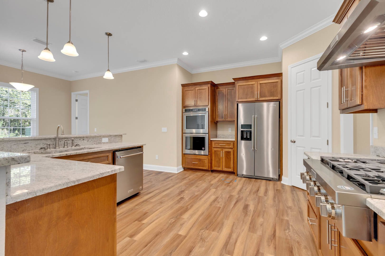 Kitchen featuring stainless steel appliances, marble countertops, wood flooring, white cabinetry, and double-door refrigerator