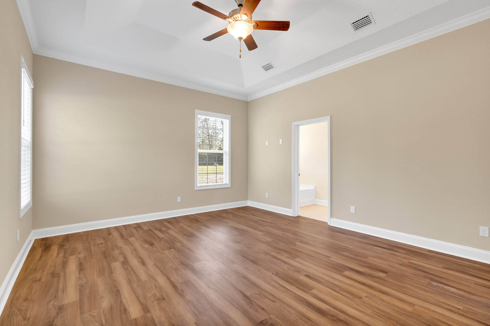 Ceiling fan with light fixture above hardwood floor, white walls, window with closed blinds, and white door frame in residential room