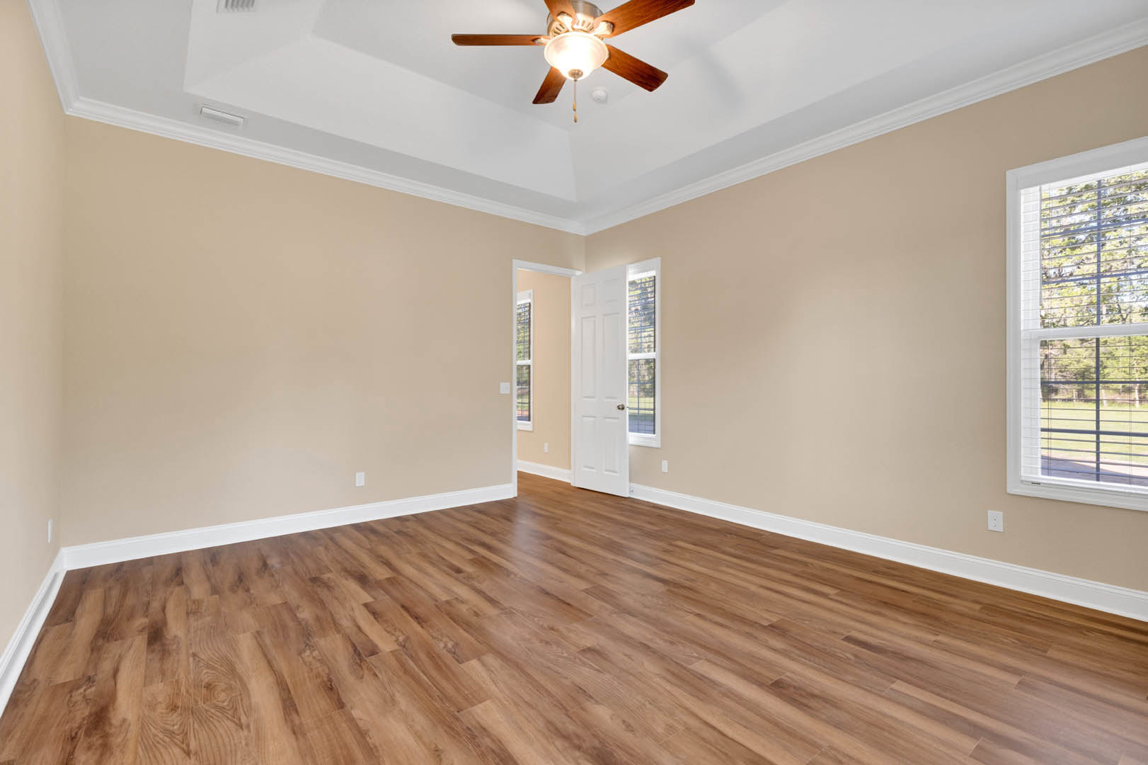 Ceiling fan with light fixture, wood flooring, white-framed window with blinds, neutral walls