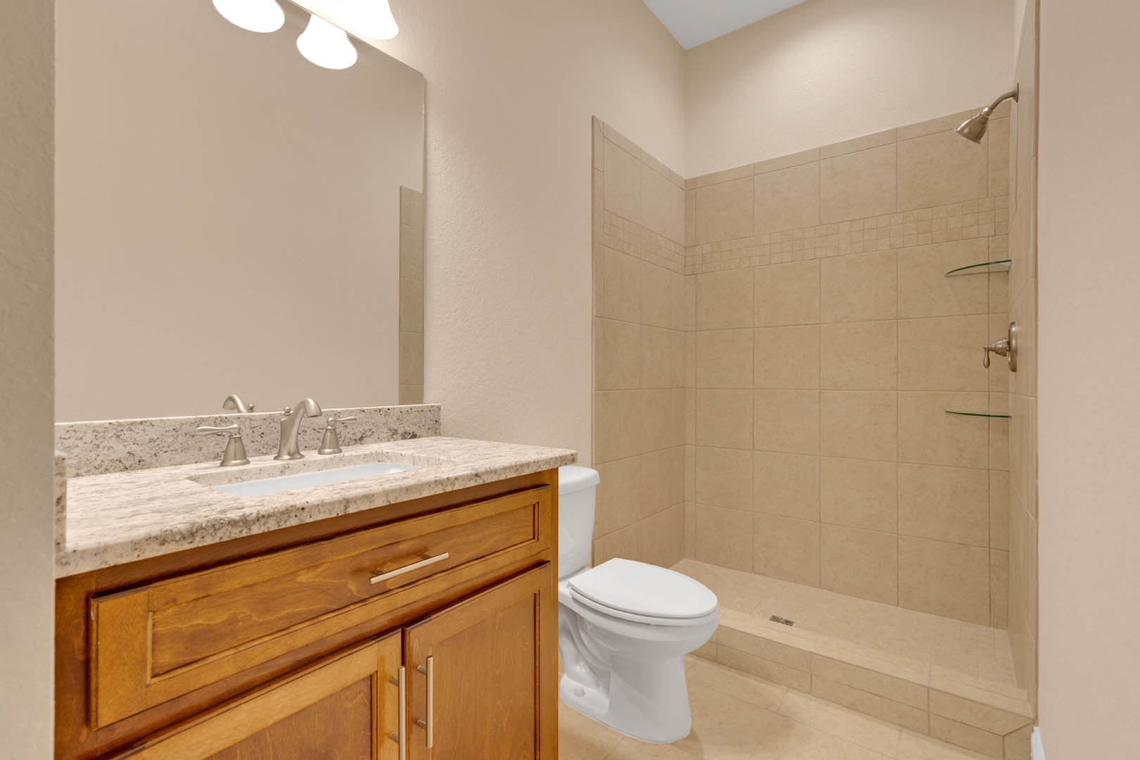 Modern bathroom featuring a white ceramic sink with chrome faucet, glass-enclosed shower with tiled walls, and a sleek toilet with a white lid.
