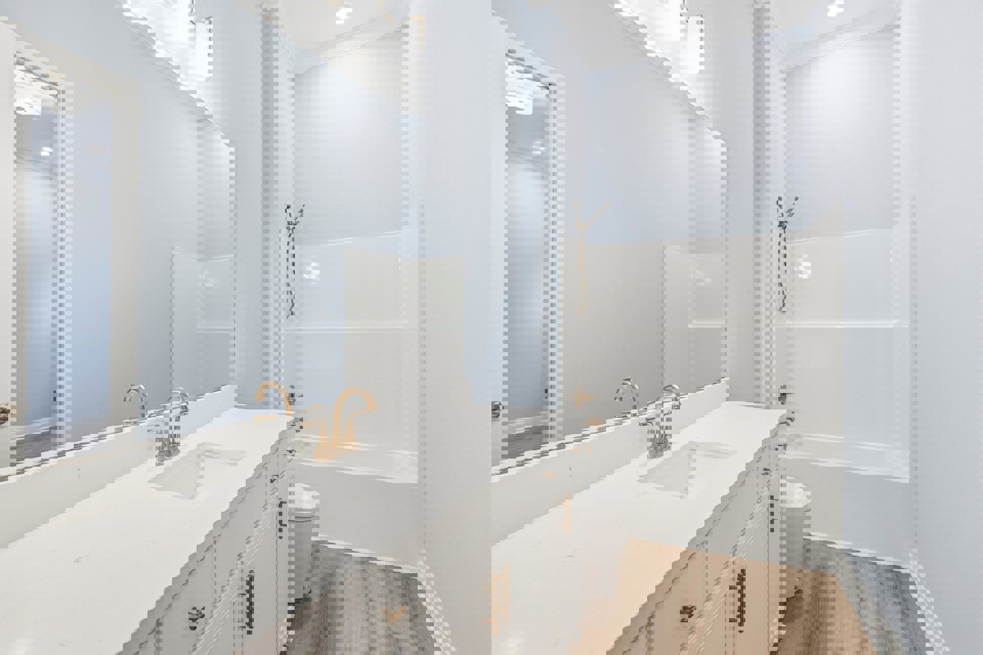 Bathroom with white tile walls, gold faucet sink, white toilet, wall-mounted shower head with hose, and white bathtub.