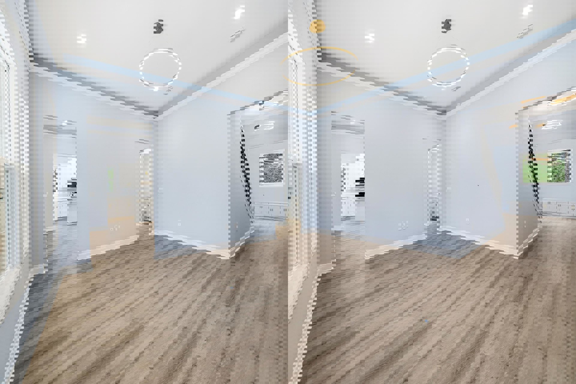 Wood flooring and light blue plaster wall in a residential room, circular ceiling light fixture, window with white trim