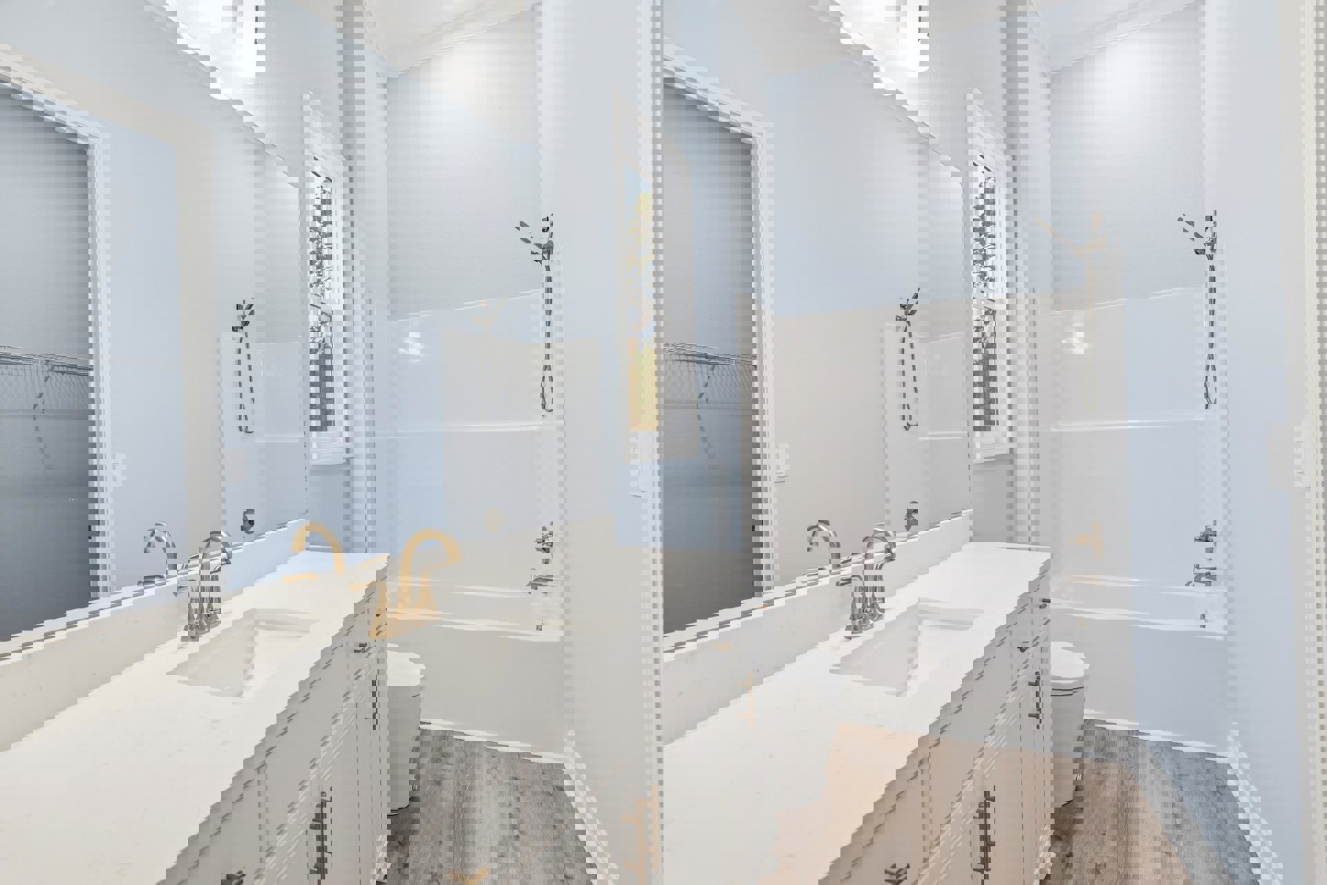 Modern bathroom with white porcelain sink and chrome faucet, wall-mounted metal shelf, tiled shower with glass door and silver shower head, white toilet, large window overlooking