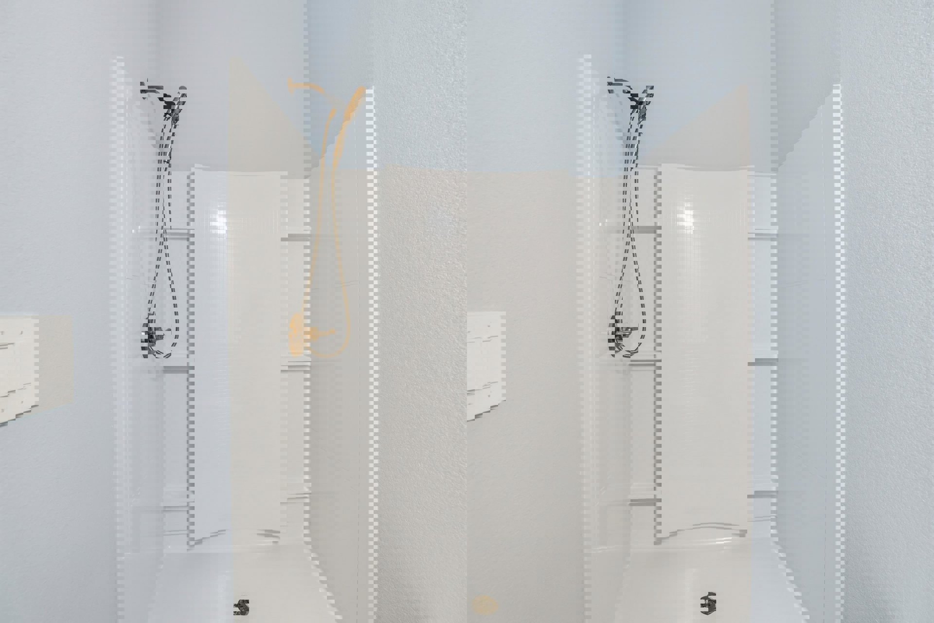 Modern bathroom shower with dual chrome shower heads mounted on white tile wall