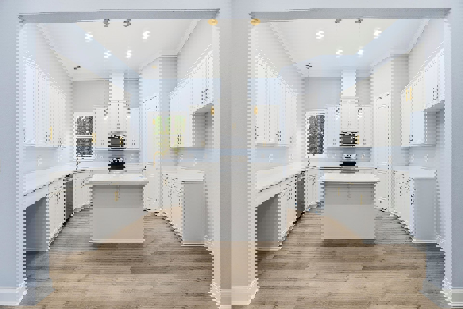 Kitchen featuring white cabinetry, wood flooring, large central island with white countertop, stainless steel sink and appliances, window overlooking trees, white door with silver