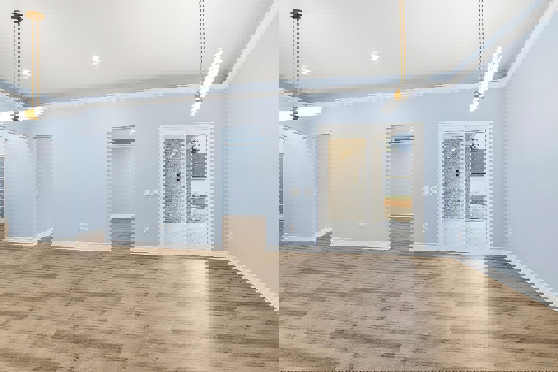 Wood floor with blue walls, white ceiling, gold-framed light fixture, glass door set in brick wall, and two wooden poles