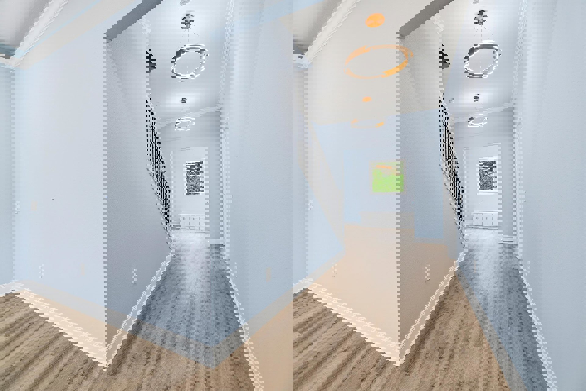 Hallway with light blue walls, wood flooring, white trim, and a modern ring-shaped light fixture; staircase visible in foreground