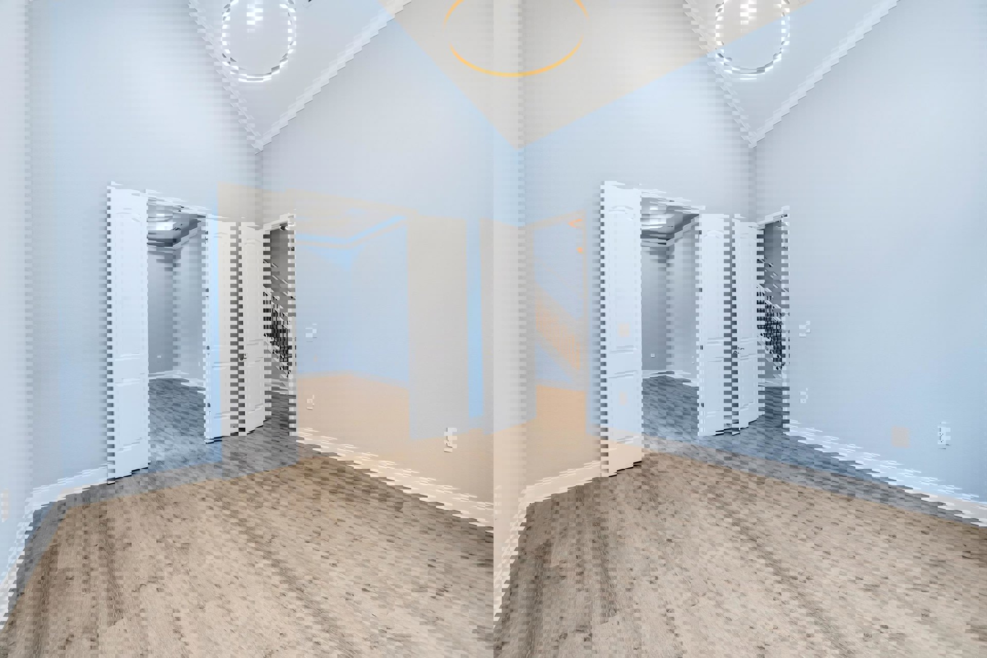 Wood flooring in a bright room with multiple white doors, silver handles, and a blue accent wall.