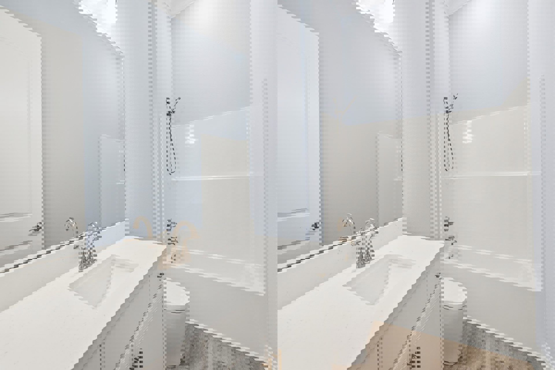 White bathroom with wall-mounted sink, white toilet, rectangular tub, chrome faucet, handheld shower head, and tiled walls.