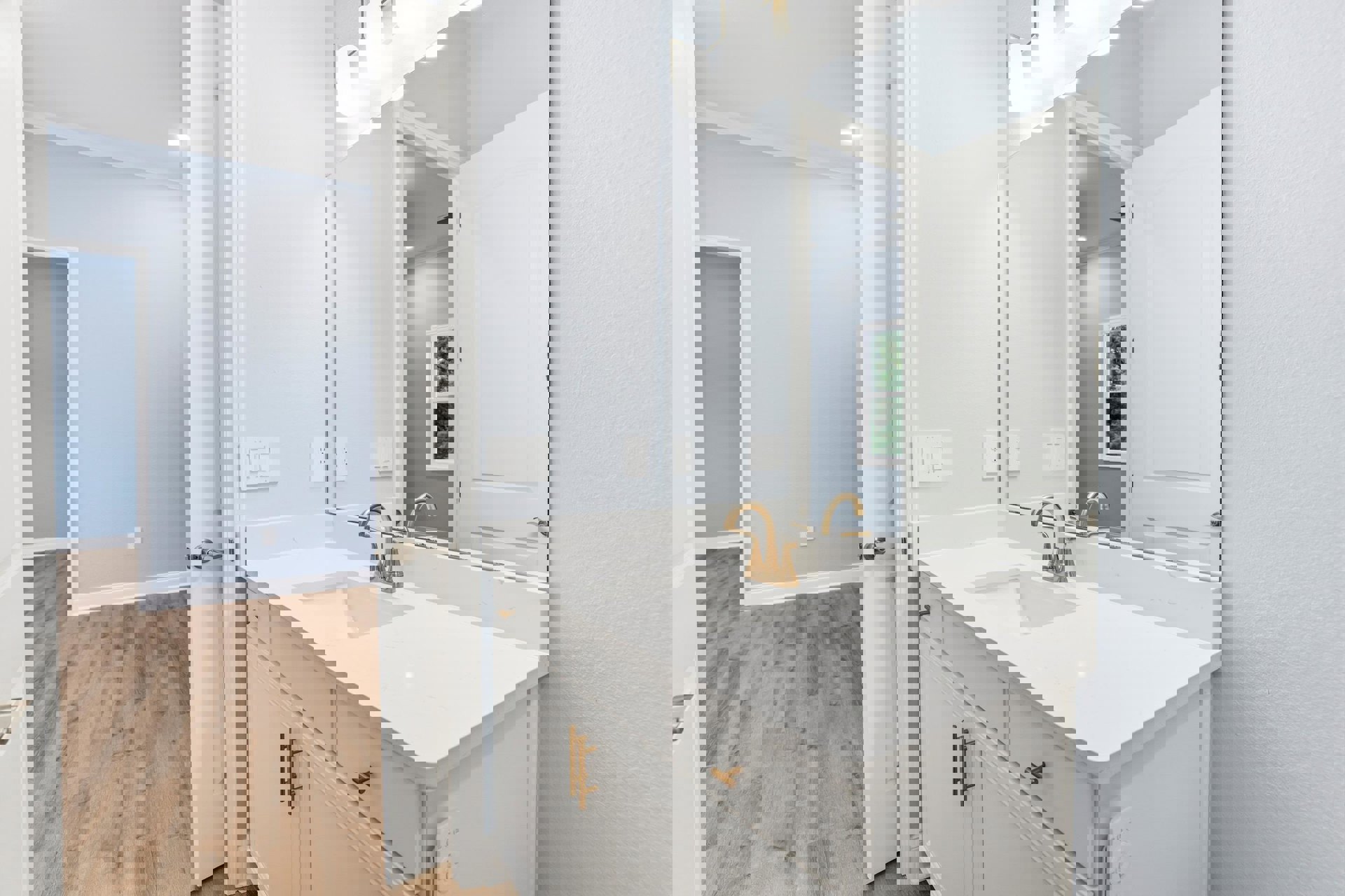 White bathroom vanity with gold faucet, white countertop, wood flooring, blue accent wall, and metal-framed mirror