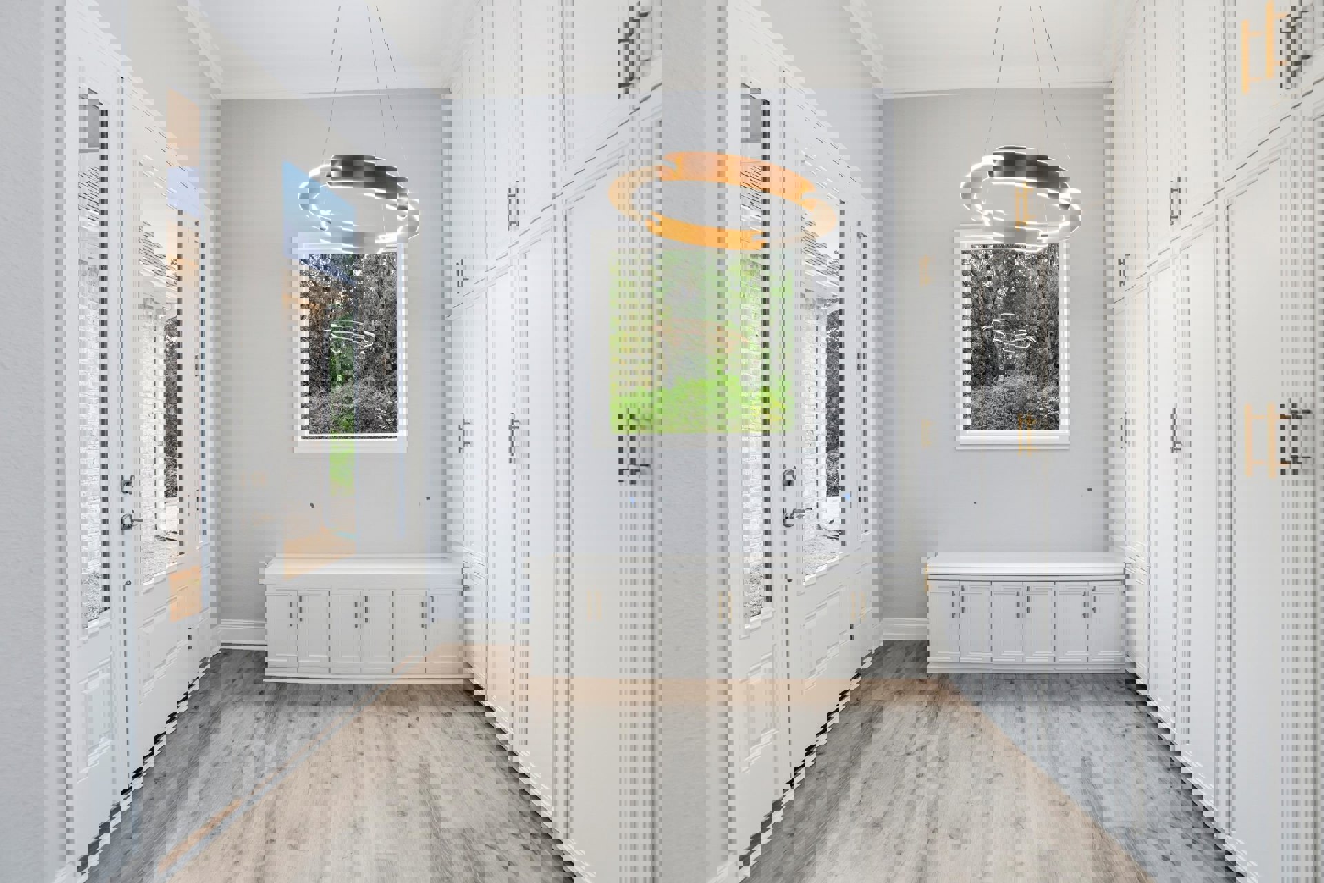 White paneled doors, gold light fixture, white cabinets with gold handles, wood flooring, white walls and molding