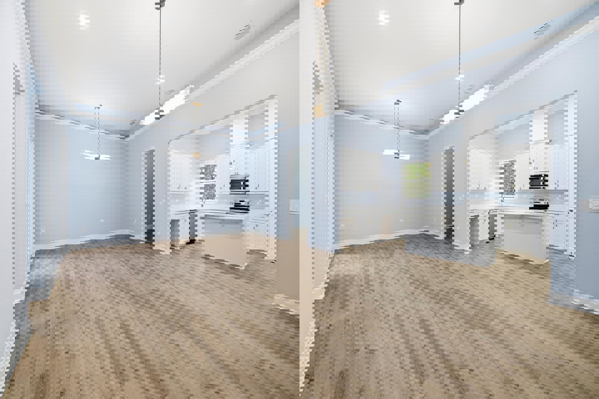 Spacious room featuring hardwood flooring, white cabinets, and a sleek white countertop; open microwave door visible near a white door frame against a blue accent wall.