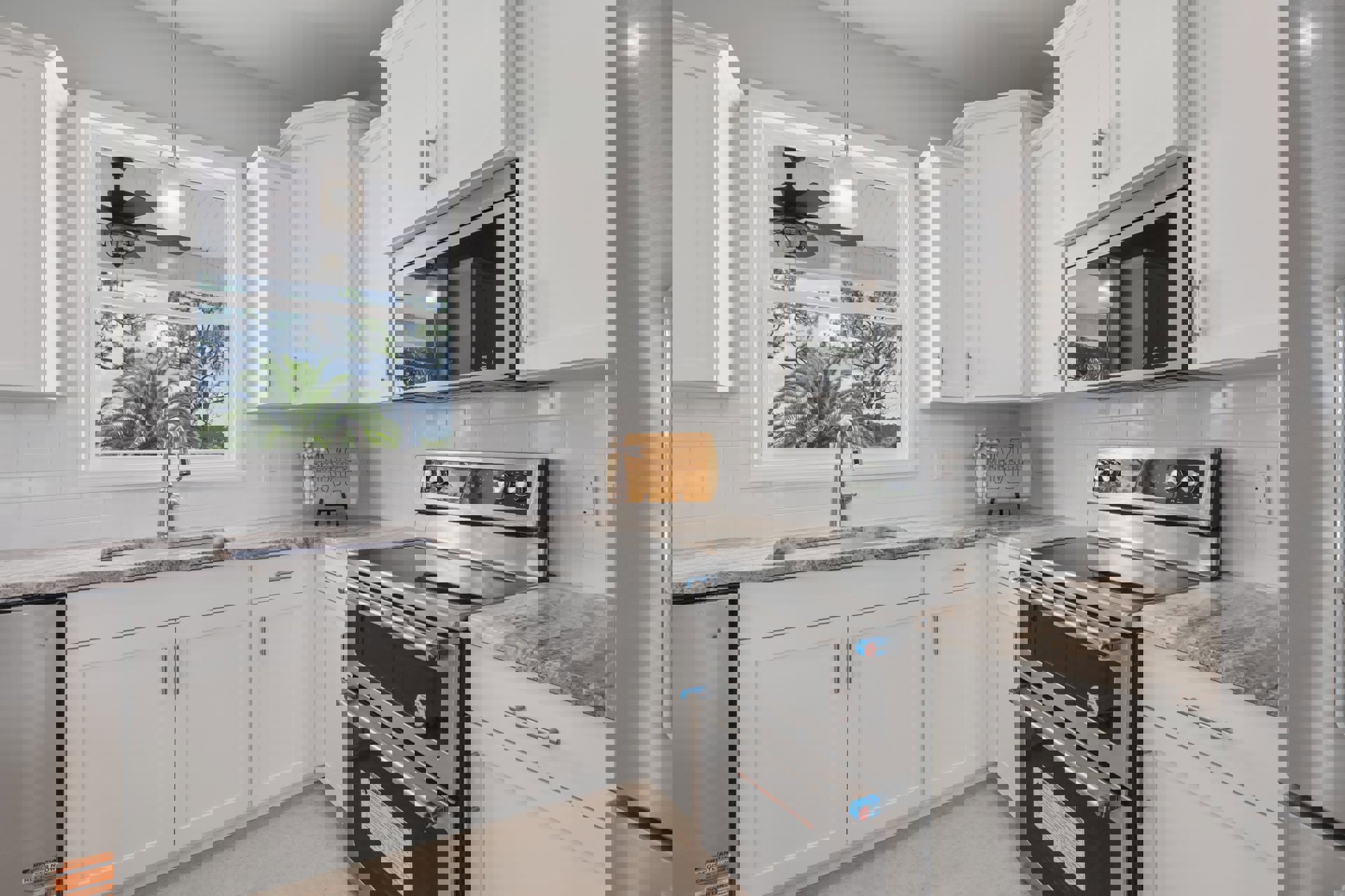 White shaker cabinets, black stove with stainless oven, microwave above, farmhouse sink under window with fan, wood sign with bow on wall, light quartz countertops