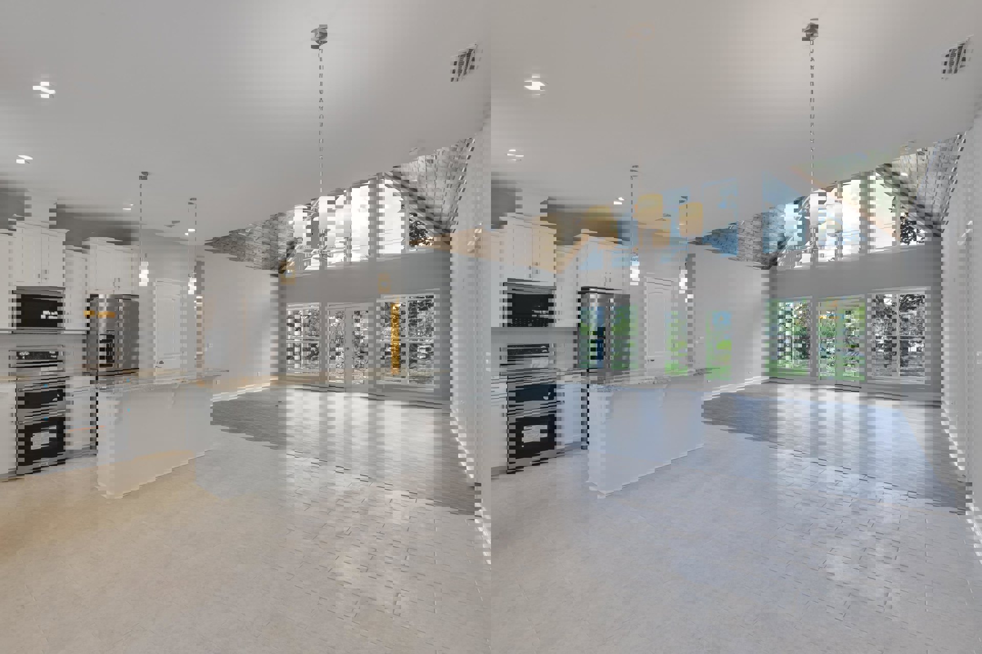 Spacious open-concept kitchen featuring a large island with white tile flooring, stainless steel refrigerator with ice and water dispenser, built-in microwave, stove, and high