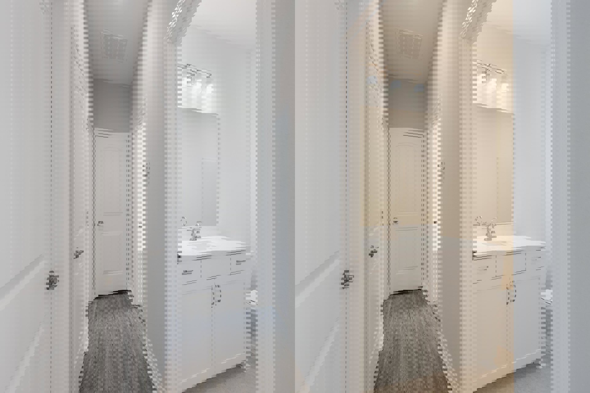 Bathroom with white walls, white cabinets, white sink and toilet, wood flooring, white door with silver handle, ceiling vent, and two-light fixture