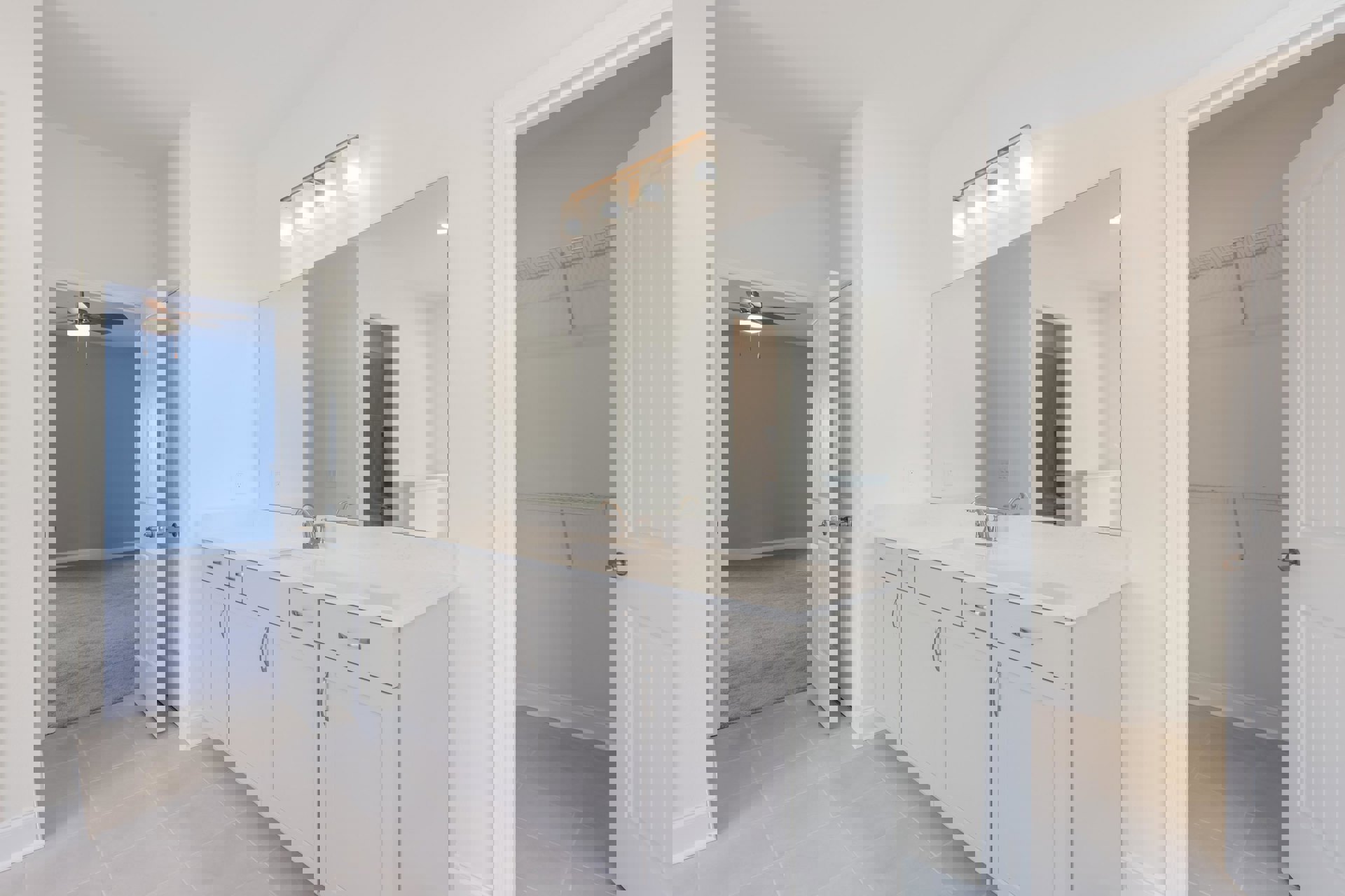 Bathroom with blue walls, large framed mirror above a white sink with silver handles, four-light fixture mounted over mirror, tile flooring, and visible cabinetry.