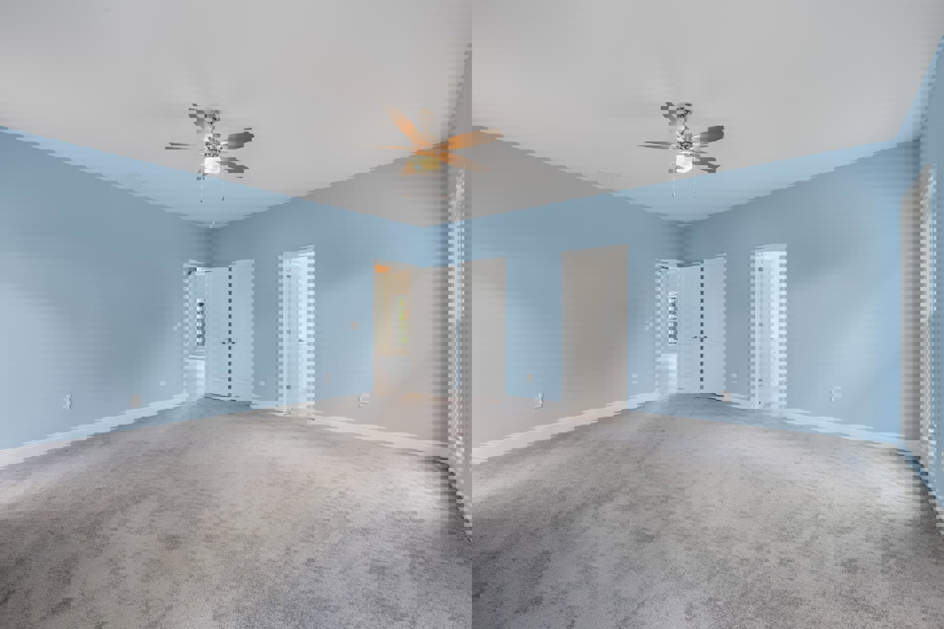 Carpeted room with blue walls, white doors with silver handles, ceiling fan with light fixture, white plaster ceiling