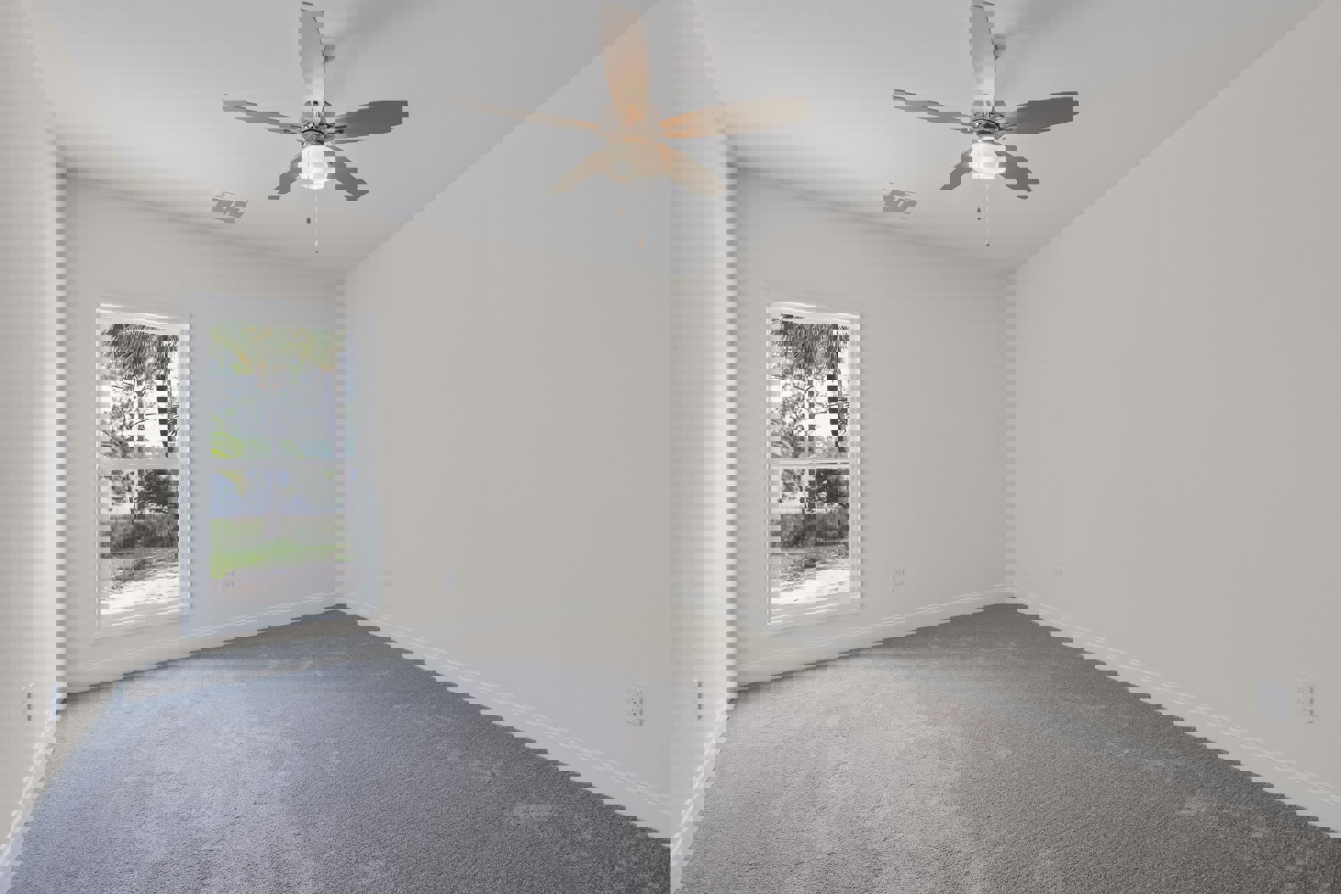 Carpeted room with white walls, ceiling fan with light fixture, large window showing green trees outside