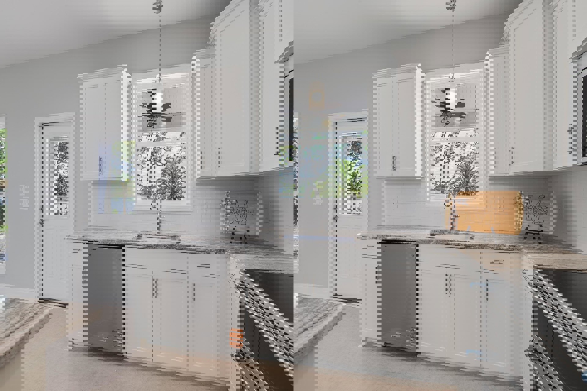 White kitchen cabinets, stainless steel sink, marble countertop, close-up oven, ceiling fan, window, wooden sign with letter, grey rectangular object with sticker, palm tree