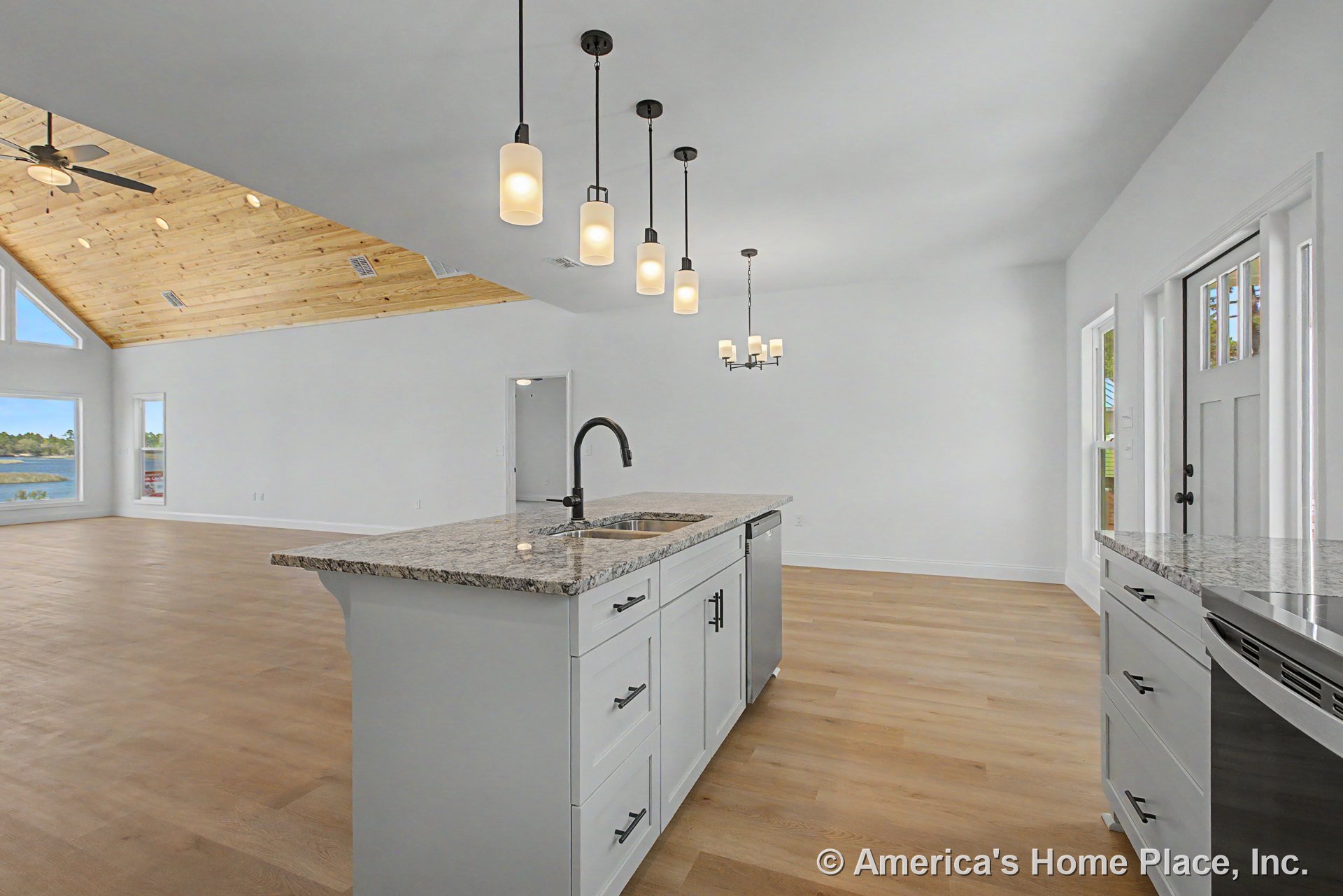 Granite island countertop with shaker cabinets and pendant lighting in an open kitchen, overlooking a vaulted living area featuring wood plank ceiling, wide plank flooring