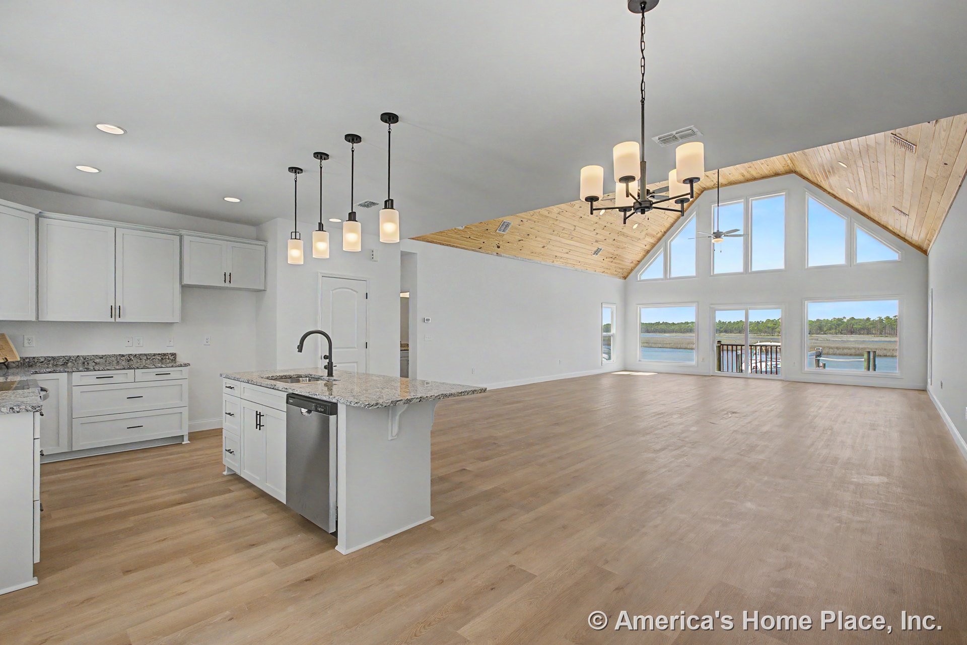 Vaulted wood ceiling and floor-to-ceiling windows highlight the open-concept living area, featuring a granite kitchen island, white shaker cabinetry, pendant and chandelier