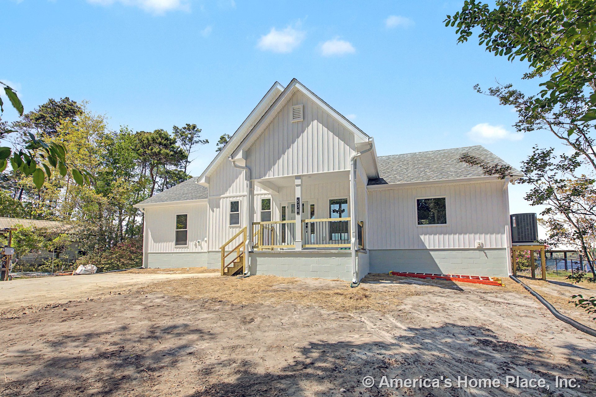 White vertical board and batten siding with covered front porch, gable roof, concrete block foundation, multiple rectangular windows, and wooden porch steps.