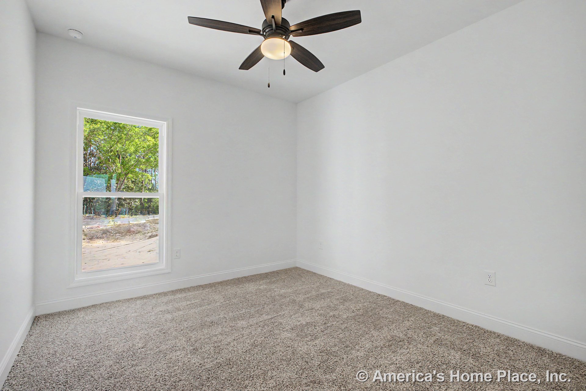 Bedroom with large window, neutral carpet flooring, white walls and baseboards, ceiling fan with integrated light, and single electrical outlet.